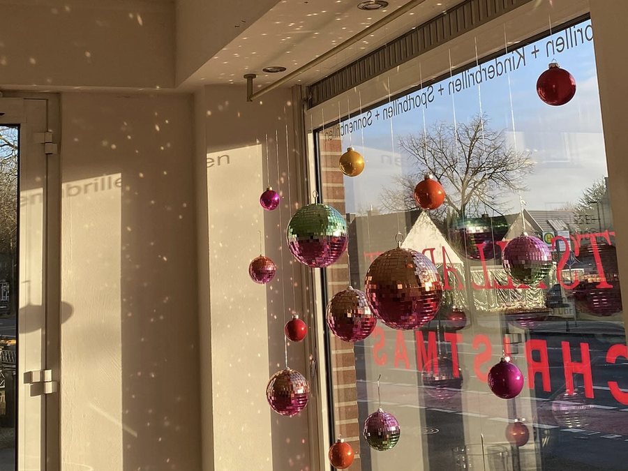 Schaufenster mit bunten Spiegelkugeln als Weihnachtsdekoration, Lichtreflexe an Decke und Wand